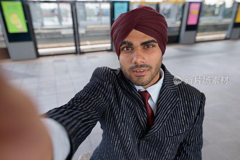 年轻英俊的印度锡克教商人戴着头巾在BTS空中火车站在泰国曼谷的肖像