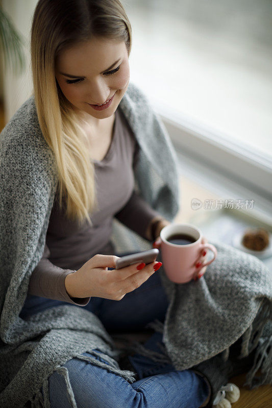 女孩拿着手机坐在地板上