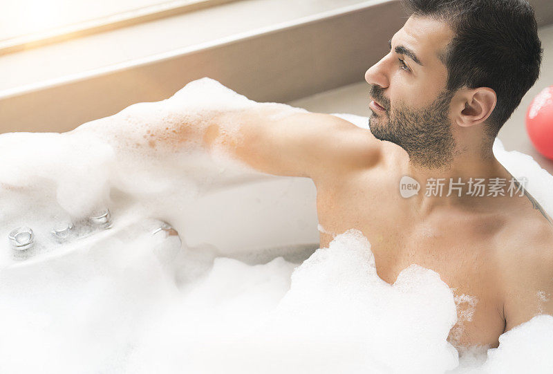 一个男人在热水浴缸里向外看