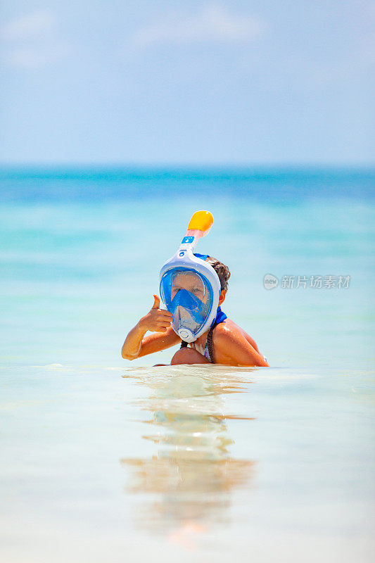 小女孩戴着水肺面具探索大海，竖起大拇指