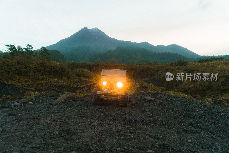 在默拉皮火山的背景上老式SUV的风景