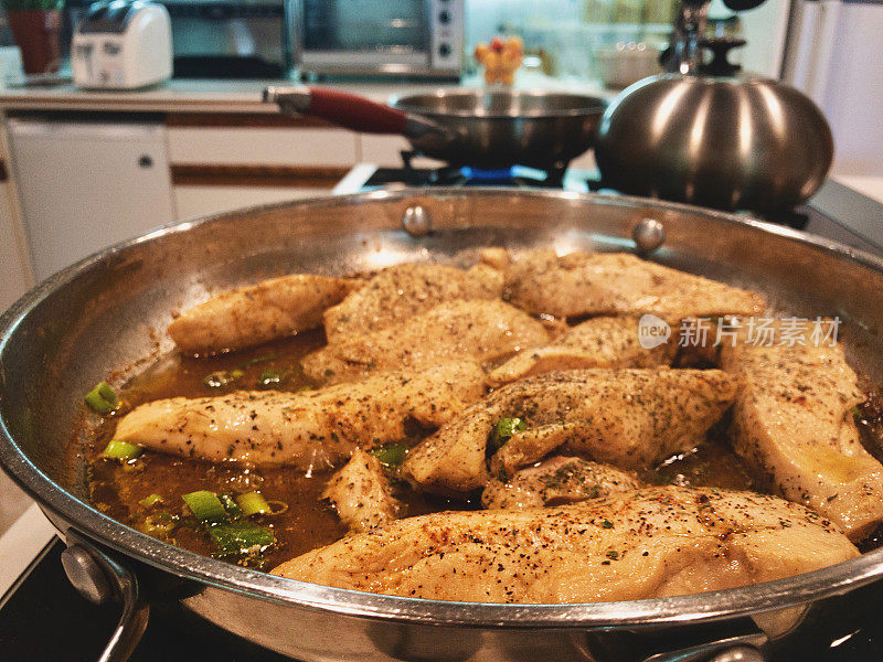 烹饪柠檬鸡类食物，在煤气炉上用不锈钢平底锅烹饪