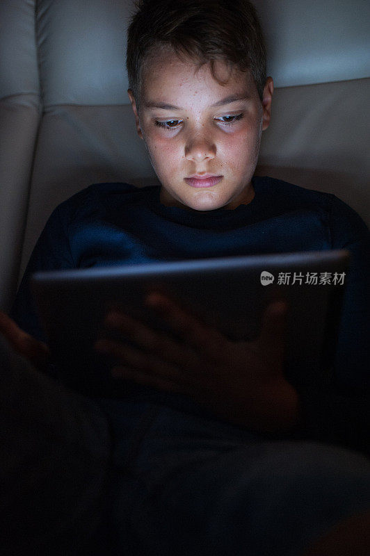 十几岁的男孩在晚上使用电子桌子