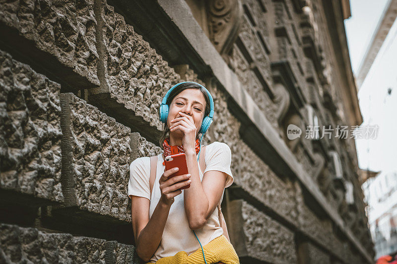 一名年轻女子正带着她的智能手机走在城市的路上