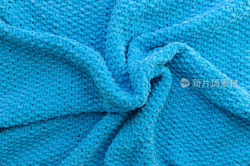 用长毛绒纱制成的亮蓝色针织格子呢。软材料。羊毛质地。手工工艺。爱好的主题。图像的背景。