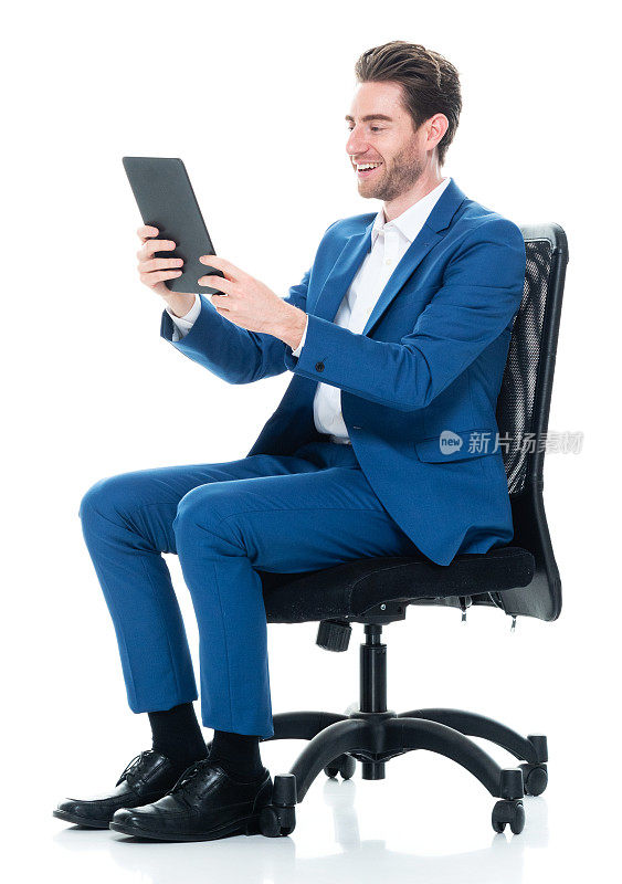 白种年轻男性商人正在休息，穿着纽扣衬衫，使用数码平板电脑
