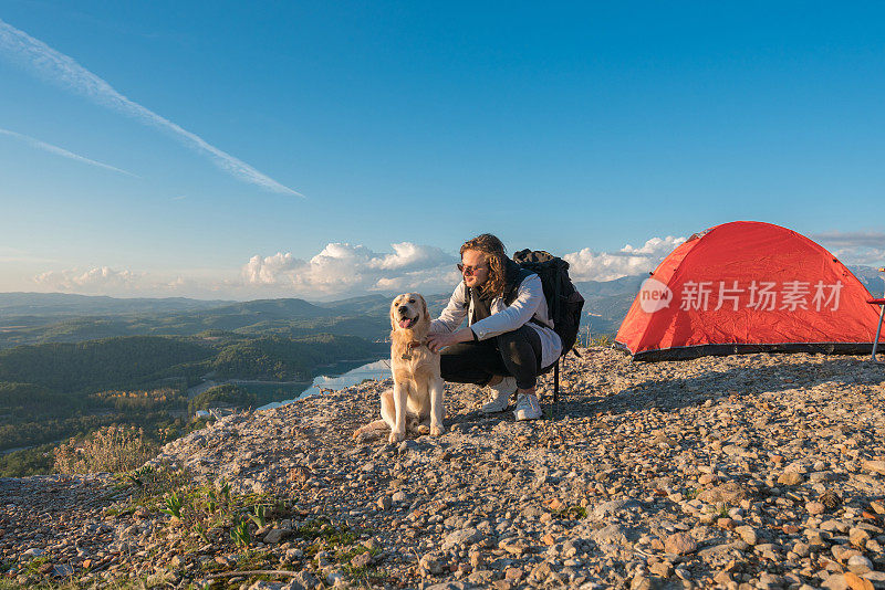 一个年轻人和她的狗在山顶露营