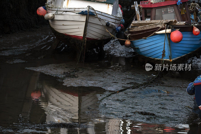 两艘旧木船停泊在港口的泥地上