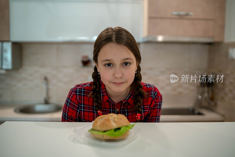 十几岁的女孩看着开胃的汉堡躺在她面前的桌子上