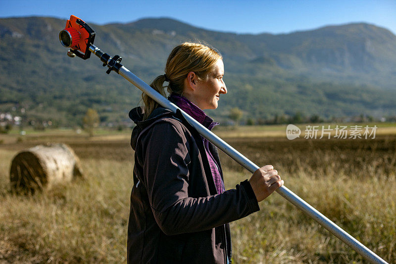 成年女性测量员在农田中携带棱镜测量工具
