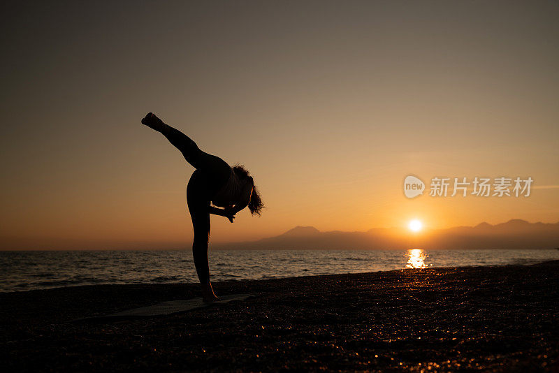 成年妇女在日落时在海滩上沉思的全长照片