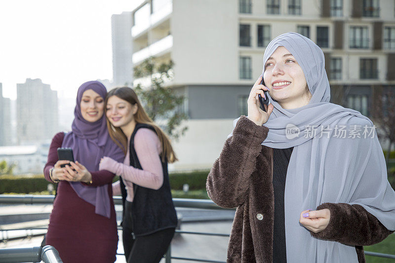 三个漂亮的穆斯林女孩玩智能手机