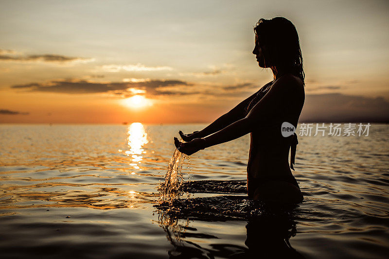 一名年轻女子举起双手，在海里举水