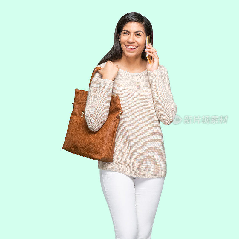 拉丁美洲和西班牙裔的年轻女性穿着暖和的衣服，拿着钱包和使用手机