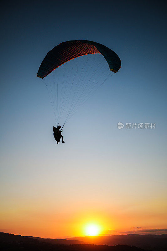 Sliüet人在天空中飞行与滑翔伞和极限运动在日落