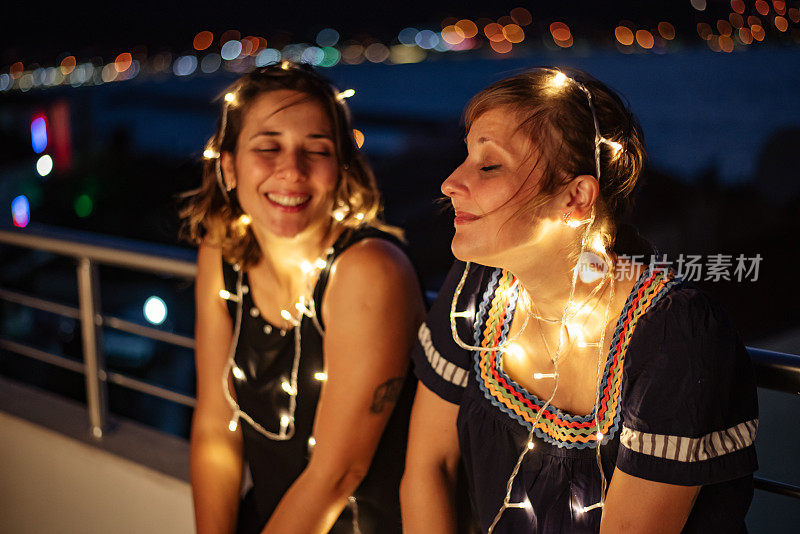快乐的女人在晚上的屋顶派对上玩灯