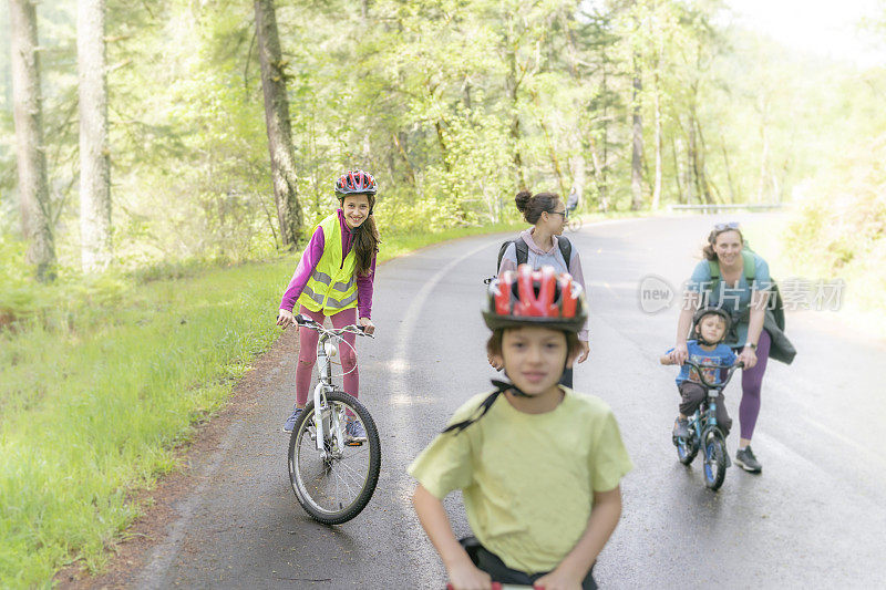 孩子们和他们的妈妈在乡村公路上骑自行车