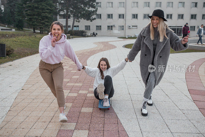 年轻女人用滑板拉着朋友