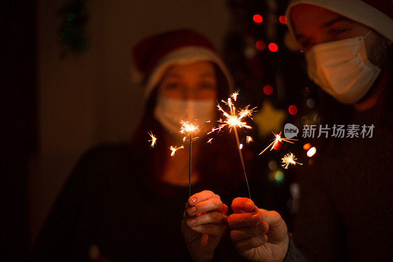 幸福的家庭在医疗面具和烟花庆祝圣诞节或新年。