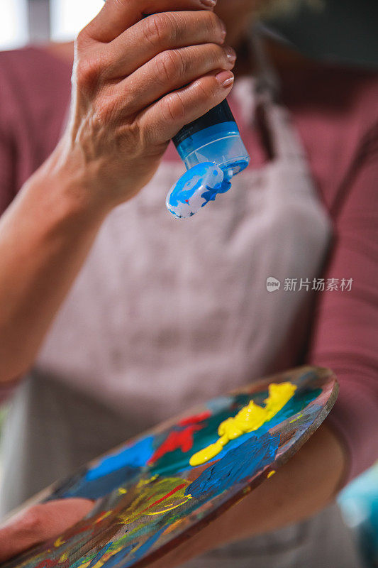 女人在画家的调色板上涂蓝色颜料