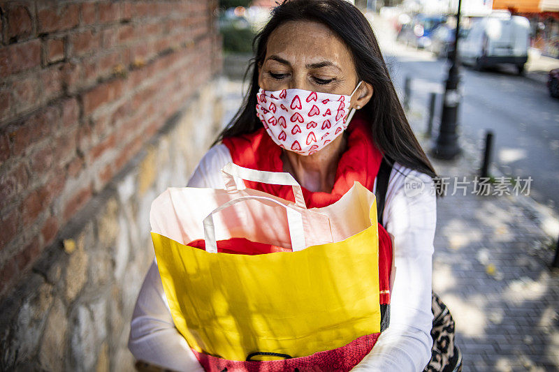 一名皮肤有白癜风的老年妇女戴着防护口罩——她买了一副防护口罩回来，因为冠状病毒大流行