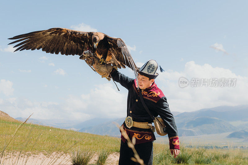 在中亚山区，身穿传统服装的老鹰猎人和老鹰在一起