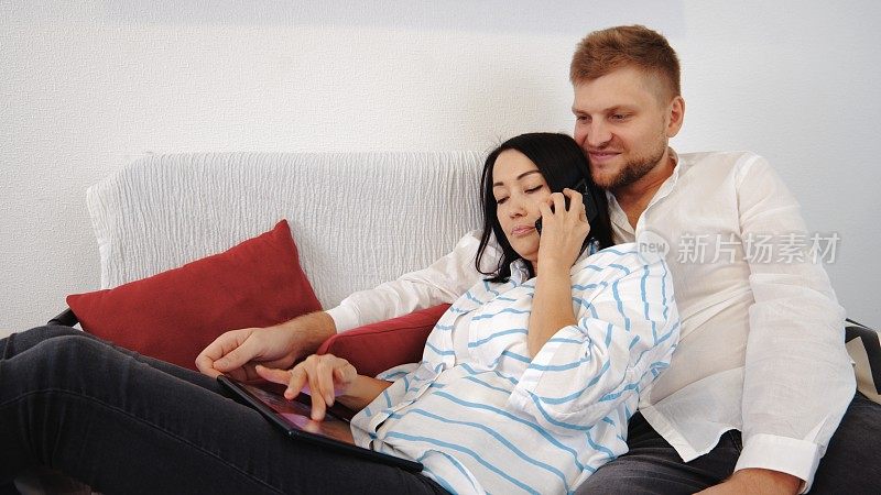 夫妻俩躺在沙发上用智能手机聊天