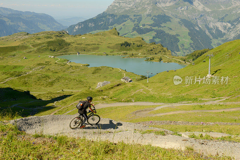 一名男子骑着山地车从瑞士阿尔卑斯山脉的约赫帕斯(Jochpass)穿过恩格尔堡(Engelberg)，沿着水流轨迹行驶