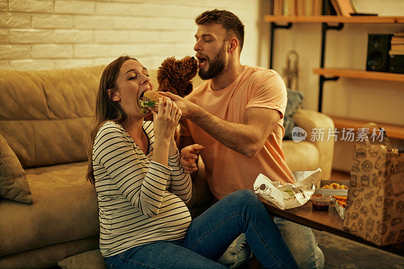 一对怀孕的夫妇正在吃外卖，旁边有狗