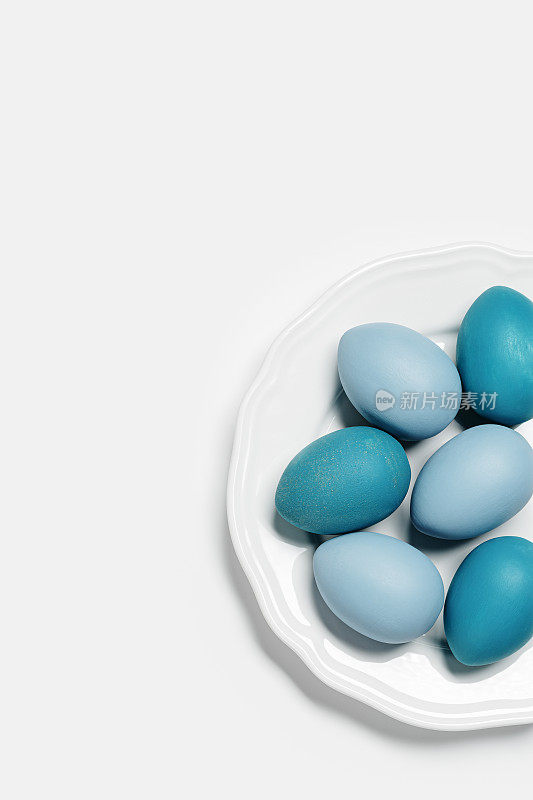 染色复活节蛋柔和的颜色蓝色，灰色，米色在圆形的白色盘子。复活节节日理念快乐，庆祝美食，装饰鸡蛋，中性新潮彩卡。顶视图表
