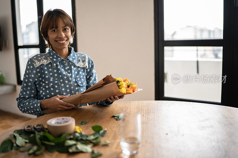 肖像的年轻妇女安排和包装鲜花在家里