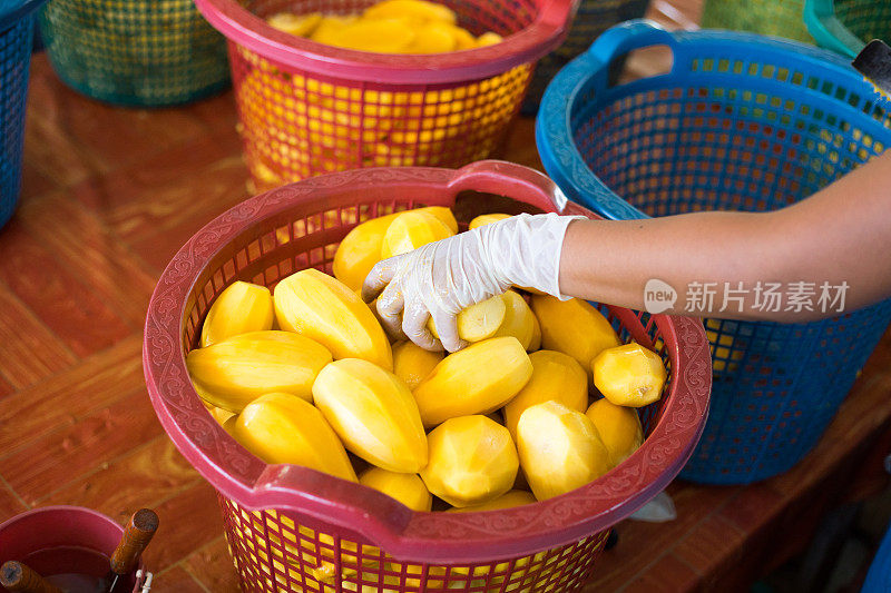 一个泰国农场工人正在清洗和切割芒果