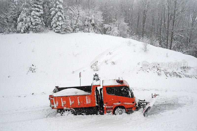 红色除雪车卡车，在冬季打开穿过森林的道路。
