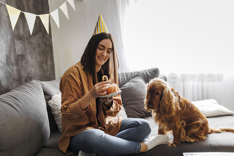 微笑的女人和她的狗在家里庆祝她的狗生日。