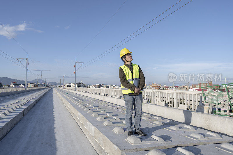 一位亚洲男性工程师在一个未完工的铁路工地上工作