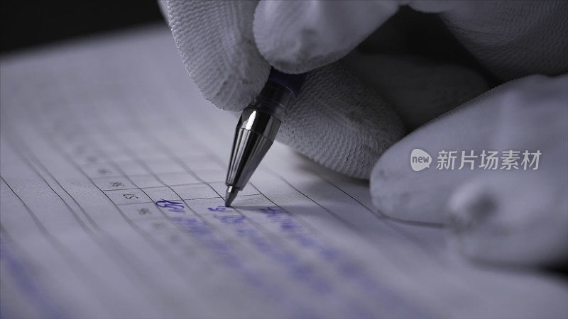 在航海日志簿上做笔记的手的侧视图。资料片。特写的手在白手套写在笔记本上的数据与笔在黑色背景。