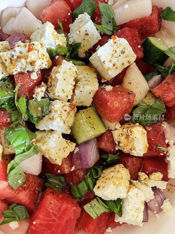 西瓜沙拉的全框图像，切片黄瓜，红洋葱，羊乳酪块，薄荷叶和黑橄榄，提高的观点