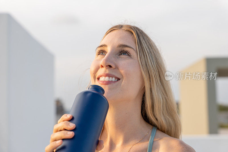 年轻女子用可重复使用的瓶子喝水的肖像