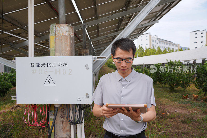 工程师在太阳能电池板前用平板进行检查