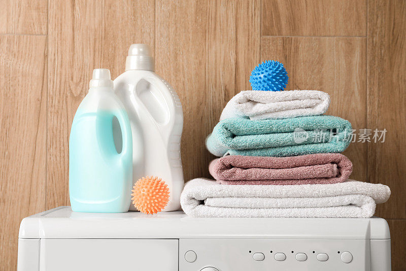 洗衣机上的干衣球、叠好的干净毛巾和清洁剂