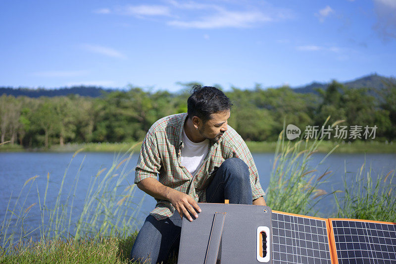 男子在户外露营，太阳能电池板正在充电。