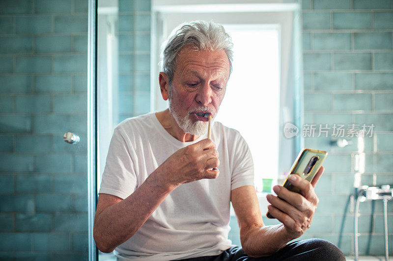 老人在浴室边刷牙边用智能手机