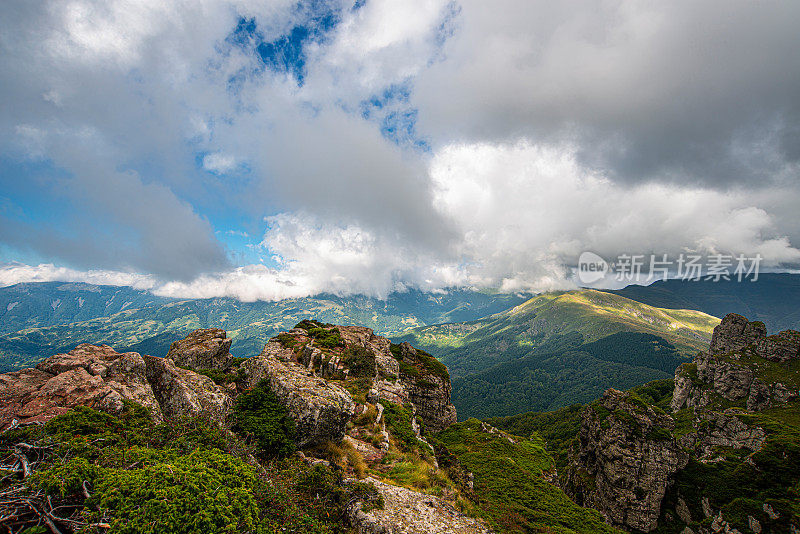 在一个阳光明媚的夏日里，有美丽的山峦和岩石景观。