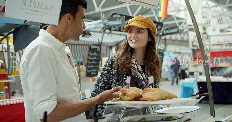 微笑的游客在伦敦市场购买食物