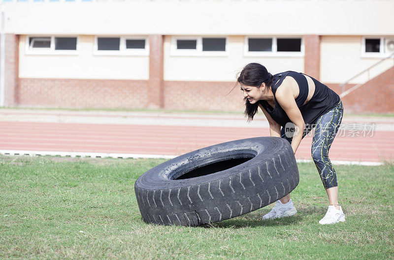 年轻活泼的女性健美运动员翻转拖拉机轮胎