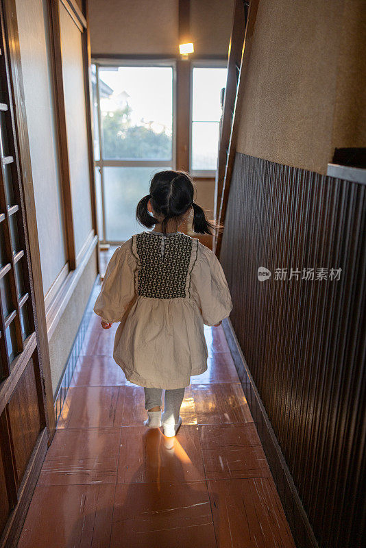 小女孩走在走廊的传统日本房子的后视图