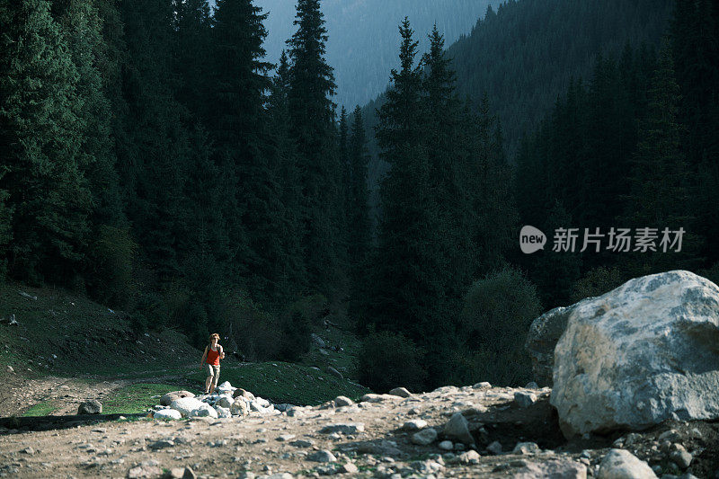 女游客在山河岸边徒步旅行并拍摄自己的视频