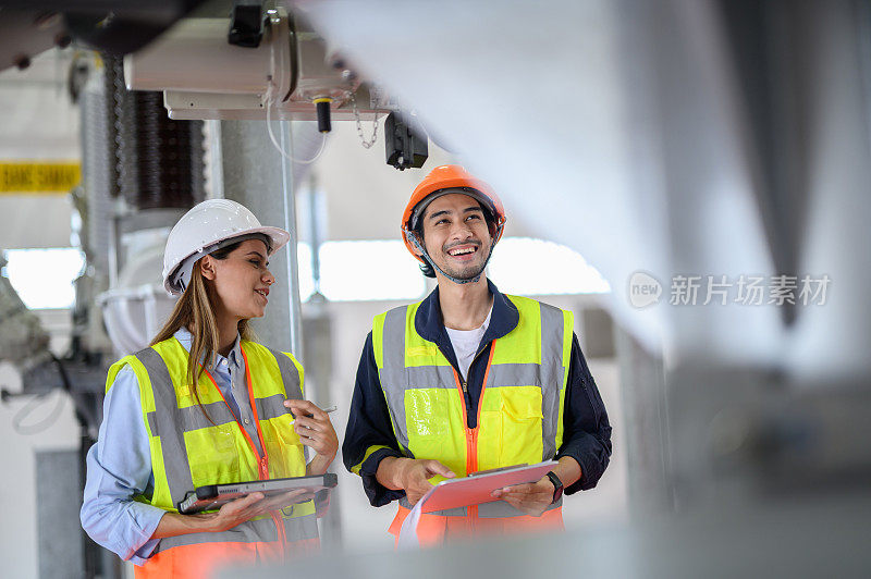 高加索电气女工程师和亚洲男技术员带着个人安全设备使用数码平板检查表操作或检查高压变电站高压断路器开关状态。