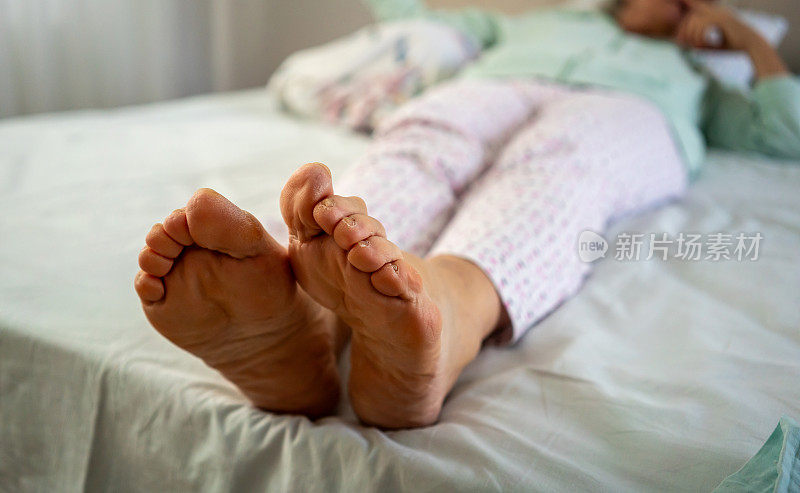 老妇人的脚是前景，她还在床上横着