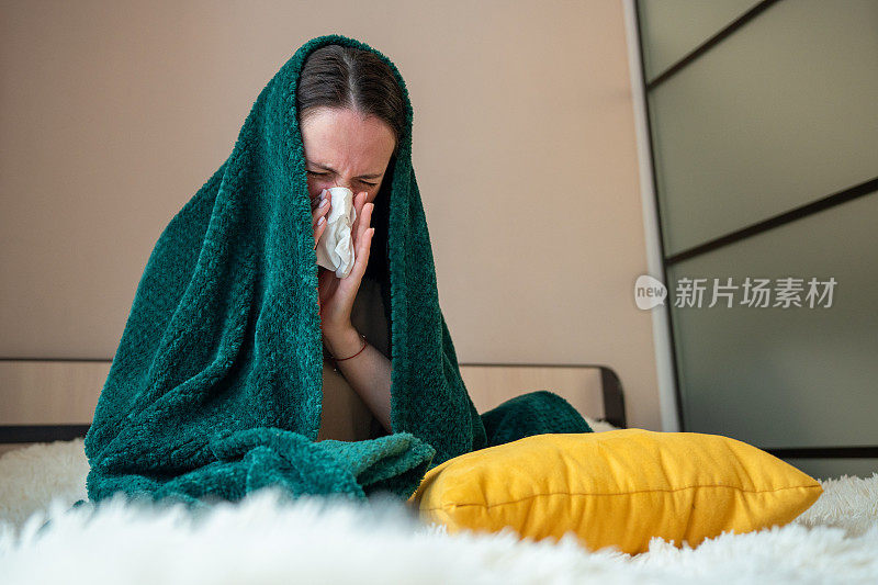 流鼻涕。生病的女孩坐在卧室的床上，用纸巾擤鼻涕